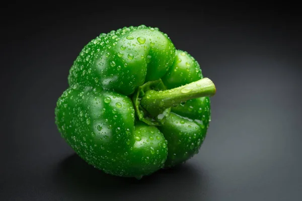 Pimenta verde fresca com gotas de água em um fundo preto — Fotografia de Stock