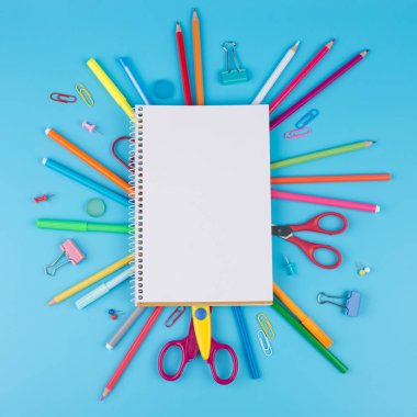 Mavi bir arka plan üzerinde renkli okul malzemeleri. Okul konseptine geri dönelim. Metin için yer ile mavi arka plan üzerinde bir kağıt üzerinde renkli okul malzemeleri