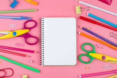 Metin için yer ile pembe arka plan üzerinde bir kağıt üzerinde renkli okul malzemeleri. Farklı renklerde kırtasiye. Okul konseptine geri dön.