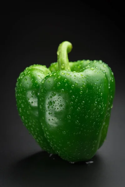 Färsk grön paprika med vattendroppar på svart bakgrund — Stockfoto