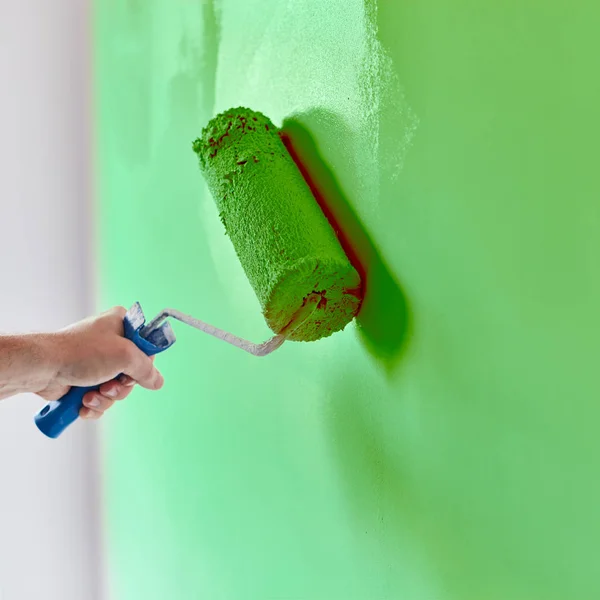 Male hand painting wall with paint roller. Painting apartment, r