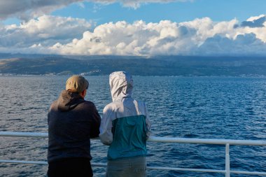 Betwe'yi işleten feribotun korkuluklarında duran iki kişi