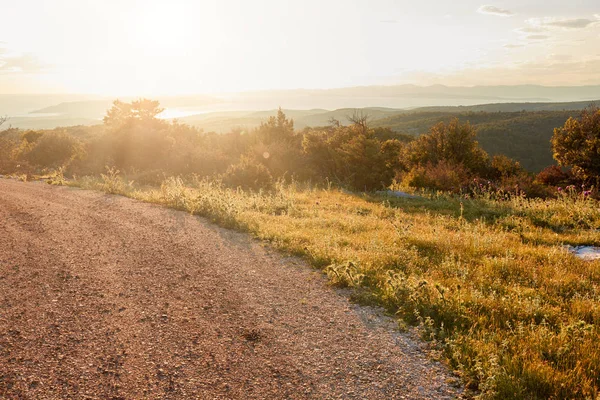 The sun sets over a country road. Mediterranean vegetation — Stock Photo, Image