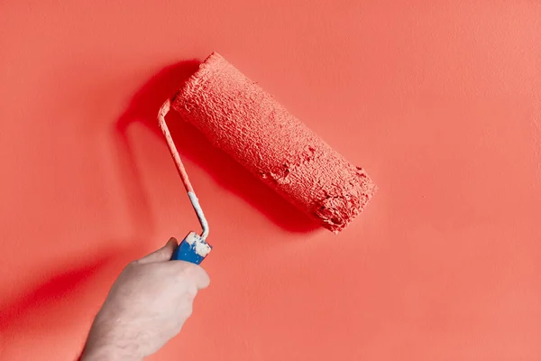 塗装ローラーと男性の手の絵画の壁 絵画のアパート ピンク色の塗料で改装 — ストック写真