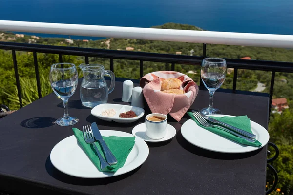 Table prepared for two people on the restaurant terrace overlooking the sea coast of the island of Corfu in Greece. On the table coffee, water and olive paste with bread