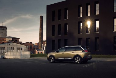 Katowice / Poland - 06.03.2017: Golden Peugeot 5008, yedi kişilik SUV, modern siyah ofis binası Porcelana Slaska Park 'ın altındaki otoparkta. Arkada eski fabrika binalarını görebilirsiniz.