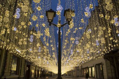 Noel süsler ve ışıklar Nikolskaya Street, Moskova. Arka plan mavi gökyüzü ile güzel sokak fenerler
