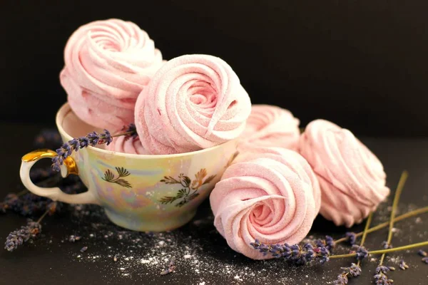 Pink zefir with lavender sprigs and a teacup on a black background