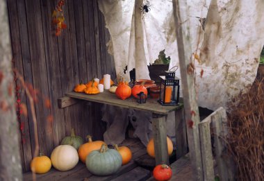 Balkabakları masanın üstünde ve masanın altında ahşap bir kulübenin verandasında, mumlar, fener, Cadılar Bayramı konsepti