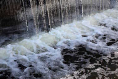 Augu bir nehir çamuru altında beyaz köpük ile düşen siyah su