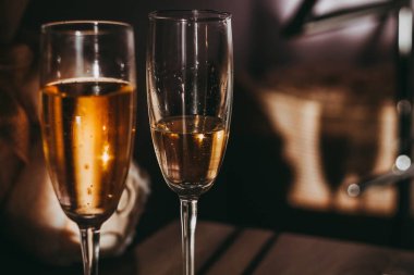 iki ayaklı büyük kadehler köpüklü şampanya ile ahşap bir yüzey üzerinde durmak ve ışıkla aydınlatılmış