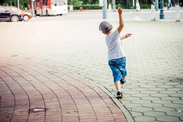 顽皮的男孩在帽子运行在人行道上挥舞着他的手臂 — 图库照片