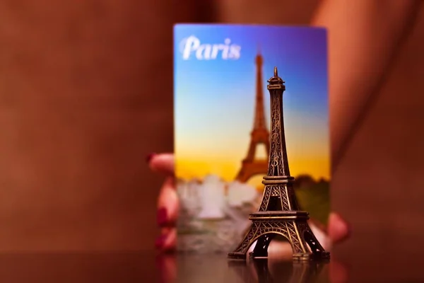kadın el resmi Eyfel Kulesi ve Hediyelik eşya yakın olan bir kartpostal tutarak