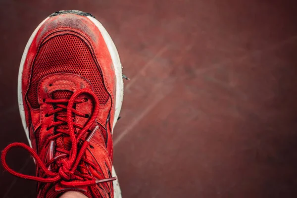 uzun bir yürüyüş ten eski bir çift eski miş olmadan kırmızı tek spor ayakkabı veya kahverengi yıpranmış arka plan üzerinde çalıştırmak