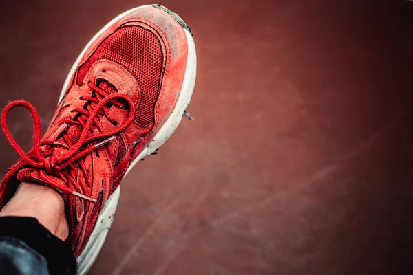 uzun bir yürüyüş ten eski bir çift eski miş olmadan kırmızı tek spor ayakkabı veya kahverengi yıpranmış arka plan üzerinde çalıştırmak