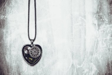 eski antik duvarda bir ip üzerinde kalp şeklinde bir kolye var, ve içinde eski bir saat mekanizması; kavram fotoğraf göstermek aşk için her zaman zaman olduğunu