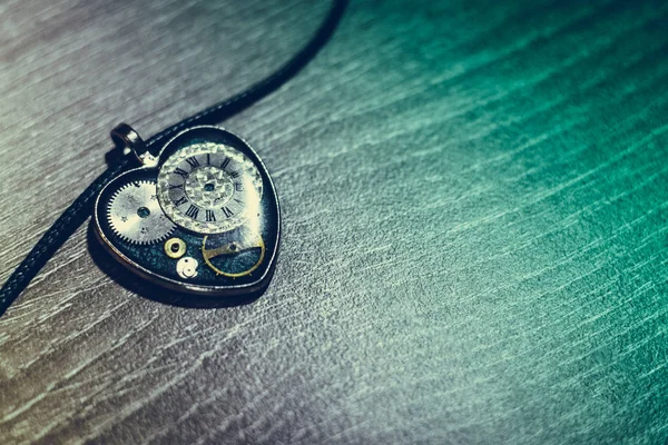 eski antik duvarda bir ip üzerinde kalp şeklinde bir kolye var, ve içinde eski bir saat mekanizması; kavram fotoğraf göstermek aşk için her zaman zaman olduğunu