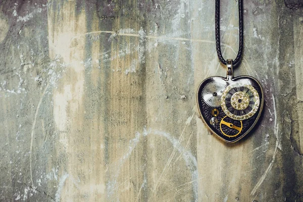 eski antik duvarda bir ip üzerinde kalp şeklinde bir kolye var, ve içinde eski bir saat mekanizması; kavram fotoğraf göstermek aşk için her zaman zaman olduğunu