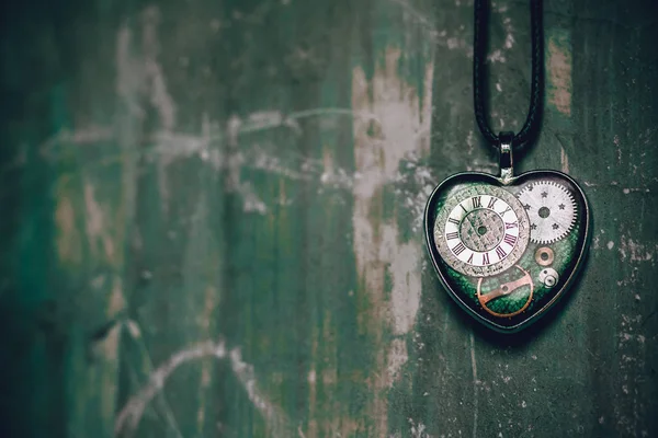 eski antik duvarda bir ip üzerinde kalp şeklinde bir kolye var, ve içinde eski bir saat mekanizması; kavram fotoğraf göstermek aşk için her zaman zaman olduğunu