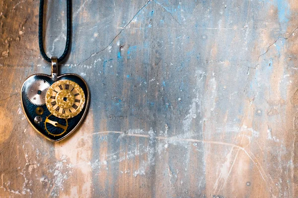 eski antik duvarda bir ip üzerinde kalp şeklinde bir kolye var, ve içinde eski bir saat mekanizması; kavram fotoğraf sonsuz aşk zamansız olduğunu göstermek