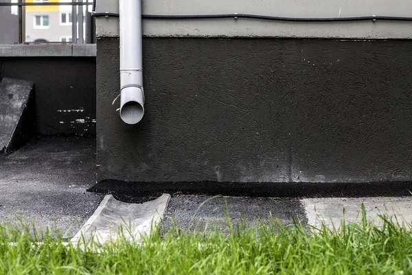 建筑物外立面和草坪前的灰色排水管 免版税图库照片