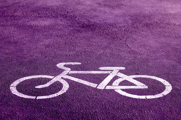 在明亮的紫色人行道上用白色油漆刻有白色油漆的自行车标志 指示指定的骑行区域 — 图库照片