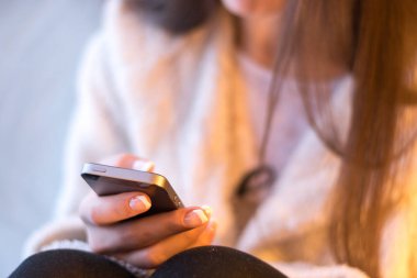 pencere önünde evde dinlenirken smartphone kullanan kadın kırpılmış atış