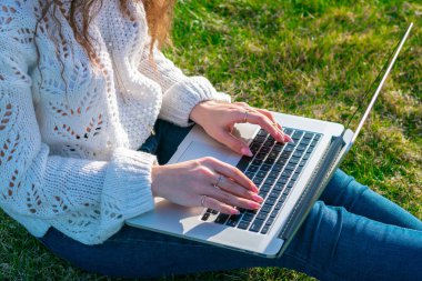 yeşil çim laptop kullanarak kadın kırpılmış shot