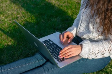 yeşil çim laptop kullanarak kadın kırpılmış shot