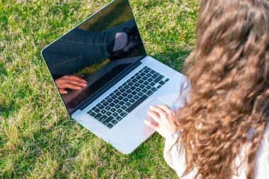 yeşil çim laptop kullanarak kadın kırpılmış shot