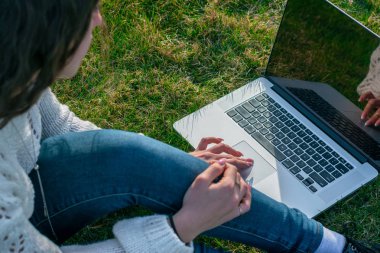 yeşil çim laptop kullanarak kadın kırpılmış shot