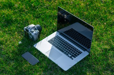 yeşil çim üzerinde akıllı telefon ve DSLR kamera ile Laptop yakın çekim
