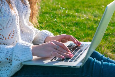 yeşil çim laptop kullanarak kadın kırpılmış shot