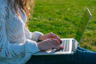 yeşil çim laptop kullanarak kadın kırpılmış shot