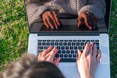 yeşil çim laptop kullanarak kadın kırpılmış shot