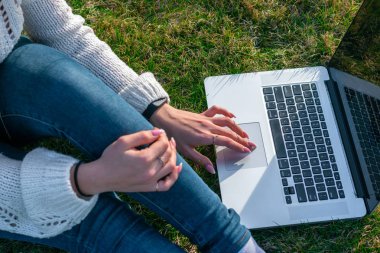 yeşil çim laptop kullanarak kadın kırpılmış shot