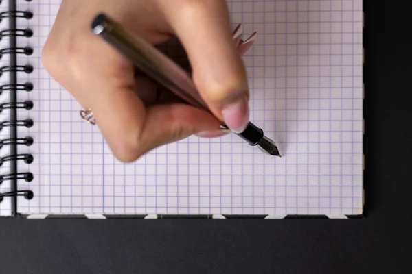 Um tiro de perto de uma mão humana a escrever algo no papel — Fotografia de Stock
