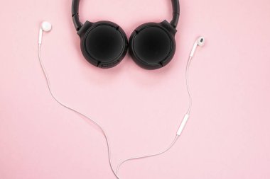 Pembe arka plandaki kulaklıkların yakın çekim. (Üstgörünüm). Müzik dinleyin. 