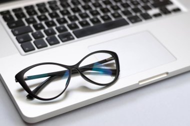 Dizüstü bilgisayar, gözlük ve diğer öğelerle ofis masasının görünümü