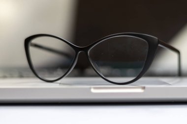 Dizüstü bilgisayar, gözlük ve diğer öğelerle ofis masasının görünümü