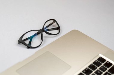 Dizüstü bilgisayar, gözlük ve diğer öğelerle ofis masasının görünümü