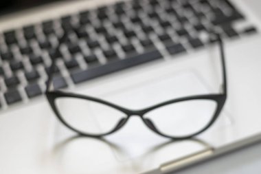 Dizüstü bilgisayar, gözlük ve diğer öğelerle ofis masasının görünümü