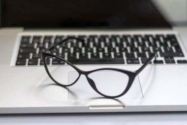 Dizüstü bilgisayar, gözlük ve diğer öğelerle ofis masasının görünümü