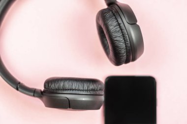Pembe arka planda kulaklıklı akıllı telefonun yakın çekim. (Üstgörünüm). Müzik dinleyin. 