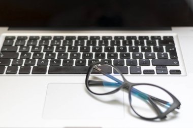 Dizüstü bilgisayar, gözlük ve diğer öğelerle ofis masasının görünümü