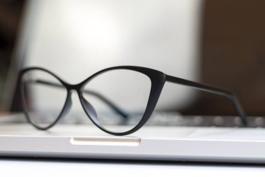 Dizüstü bilgisayar, gözlük ve diğer öğelerle ofis masasının görünümü
