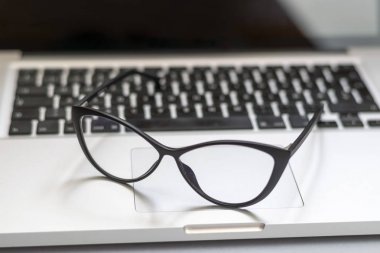 Dizüstü bilgisayar, gözlük ve diğer öğelerle ofis masasının görünümü