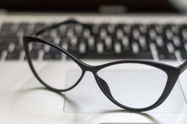 Dizüstü bilgisayar, gözlük ve diğer öğelerle ofis masasının görünümü