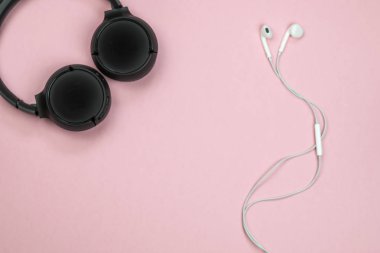 Pembe arka plandaki kulaklıkların yakın çekim. (Üstgörünüm). Müzik dinleyin. 