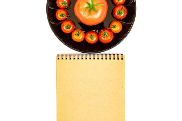 メモ帳の近くの白い背景に隔離された黒いプレートのトマト 白い背景のプレートに赤いトマトの組成 テキストの配置 — ストック写真